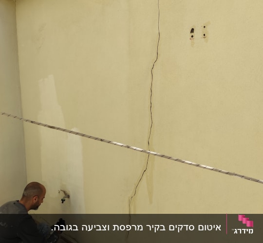 אדם צובע קיר עם סדק גדול